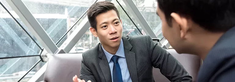 Two people in suits having a discussion in a modern office setting.