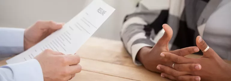 Two people seated at a table, one holding a resume.