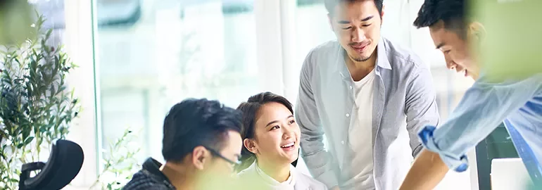 Smiling coworkers having a discussion around a table in a bright office.