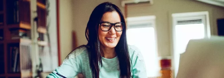 Person smiling while looking at a computer in a cozy room.