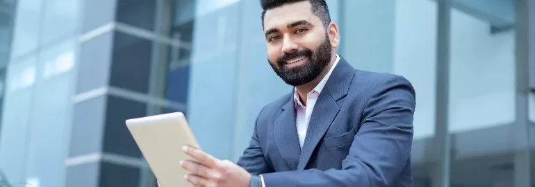 Person in a suit using a tablet outside a building.
