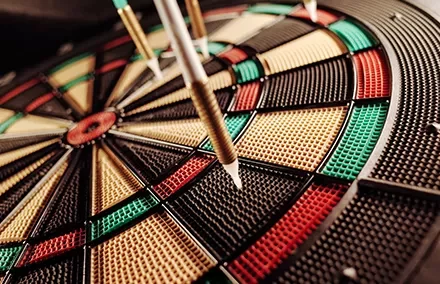 Close-up of darts on a colorful dartboard.