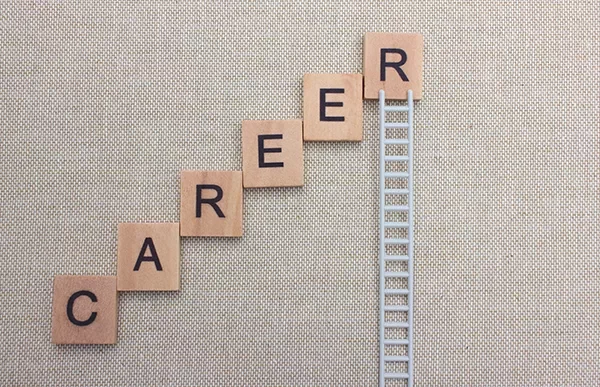 Scrabble tiles spell 'career' on a step pattern with a ladder symbolizing growth.