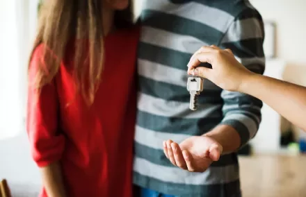 Person handing over house keys to another individual.