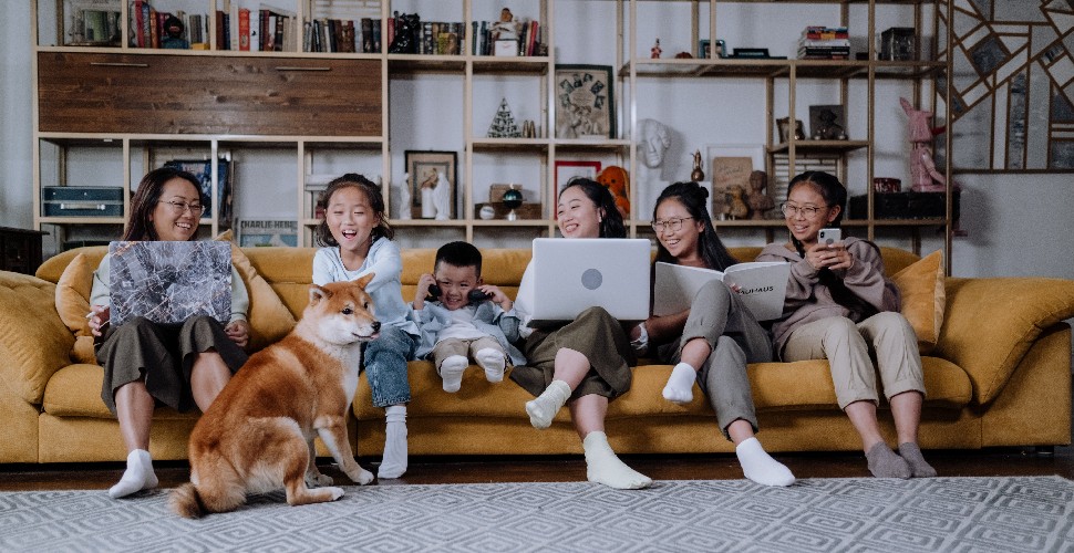 A female adult working from home and laughing with her children, playing with their pet dog